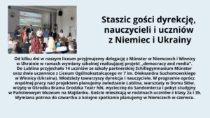 Grafika składa się z dwóch części: zdjęcia po lewej stronie oraz tekstu po prawej stronie na jasnoniebieskim tle.

Zdjęcie:
Przedstawia scenę w sali szkolnej z drewnianą podłogą i białymi ścianami. Na ścianie w tle widoczny jest ekran z projektorem, na którym wyświetlono obraz przedstawiający krajobraz z wodą i górami. Na scenie stoi siedem osób – pięć dorosłych i dwie młodsze osoby, prawdopodobnie uczniowie. Dorośli są elegancko ubrani – mężczyzna w garniturze, kobiety w swetrach lub marynarkach. Wśród nich jedna osoba trzyma mikrofon, a reszta uśmiecha się i patrzy na publiczność. Publiczność składa się z uczniów siedzących na krzesłach; niektórzy mają widoczne kolorowe ubrania, w tym dziewczyna z długimi rudymi włosami w czerwonej bluzie.

Tekst:
Po prawej stronie znajduje się blok tekstu w języku polskim. Nagłówek w dużej czarnej czcionce głosi:

„Staszic gości dyrekcję, nauczycieli i uczniów z Niemiec i Ukrainy”

Poniżej znajduje się akapit tekstu w mniejszej czcionce:

    Od kilku dni w naszym liceum przyjmujemy delegację z Münster w Niemczech i Winnicy w Ukrainie w ramach wymiany szkolnej realizującej projekt „democracy and media”. Do Lublina przyjechało 14 uczniów ze szkoły partnerskiej Schillegymnasium Münster oraz dwie uczennice z Liceum Ogólnokształcącego nr 7 im. Oleksandra Suchomowskiego w Winnicy (Ukraina). Młodzieży towarzyszy dyrekcja i nauczyciele. W programie oprócz wspólnej pracy nad projektem planujemy zwiedzanie Lublina, warsztaty w Domu Słów, wizytę w Ośrodku Brama Grodzka Teatr NN, wycieczkę do Sandomierza i pobyt studyjny w Państwowym Muzeum na Majdanku. Goście mieszkają w rodzinach uczniów z klasy 2a i 3b. Wymiana potrwa do czwartku a kolejne spotkanie planujemy w Niemczech w czerwcu.

Cała grafika jest estetycznie uporządkowana, z dobrze widocznym tekstem na kontrastowym tle, co poprawia czytelność.