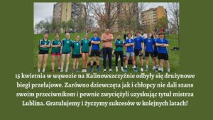 Obraz przedstawia grupowe zdjęcie młodzieży sportowej na tle zielonej trawy i wysokich bloków mieszkalnych. Całość umieszczona jest na oliwkowo-zielonym tle. Poniżej zdjęcia znajduje się blok tekstu w białym kolorze.

Opis zdjęcia:

    Na pierwszym planie, na trawie, stoi 14 osób — 6 dziewcząt, 1 dorosły mężczyzna (najprawdopodobniej trener) i 7 chłopców.

    Ustawieni są w równym szeregu, frontalnie do kamery.

    Dziewczęta stoją po lewej stronie zdjęcia. Mają na sobie zielone koszulki sportowe z białymi i czarnymi paskami na ramionach. Na koszulkach widoczne są białe numery: 9, 8, 6, 3.

    Dziewczęta noszą krótkie spodenki lub legginsy i sportowe buty.

    Pośrodku stoi dorosły mężczyzna — ubrany w różową bluzę z długim rękawem i ciemne spodnie dresowe, ręce ma skrzyżowane na piersi.

    Chłopcy po prawej stronie noszą niebieskie koszulki z białymi numerami: 7, 5, 15, 12, 6, 4.

    Wszyscy mają krótkie sportowe spodenki i buty do biegania.

    W tle widoczne są wysokie, wielopiętrowe bloki mieszkalne w kolorach szaro-beżowym i pomarańczowym oraz kilka bezlistnych lub skąpo ukwieconych drzew, co wskazuje na wczesną wiosnę.

    Na wzgórzu za grupą widać kilkanaście osób — prawdopodobnie kibiców lub innych uczestników wydarzenia.

Opis tekstu (pod zdjęciem): Tekst jest w kolorze białym, centrowany, o dużej, wyraźnej czcionce. Treść napisana poprawną polszczyzną:

„15 kwietnia w wąwozie na Kalinowszczyźnie odbyły się drużynowe biegi przełajowe. Zarówno dziewczęta jak i chłopcy nie dali szans swoim przeciwnikom i pewnie zwyciężyli uzyskując tytuł mistrza Lublina. Gratulujemy i życzymy sukcesów w kolejnych latach!”

Wrażenia dodatkowe: Zdjęcie i tekst są wyraźne, dobrze do siebie dopasowane kolorystycznie. Komunikat jest pozytywny, pełen uznania i zachęty. Układ strony jest prosty i czytelny, co sprzyja dostępności i łatwości odbioru dla osób niewidomych i słabowidzących.