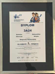 Obraz przedstawia dyplom oprawiony w czarną ramkę z metalicznym połyskiem, umieszczony pionowo. Tło samego dyplomu jest białe, tekst wydrukowany w kolorze czarnym i granatowym, z kolorowymi elementami graficznymi u góry.
Szczegółowy opis graficzny i tekstowy:
Górna część dyplomu:

Po lewej stronie znajduje się logo SIGG 23, składające się z dużych liter „SIGG” (pierwsze litery nazwy „Szkolna Internetowa Gra Giełdowa”), napisane ciemnoniebieskim kolorem, z nieco pochyloną do przodu literą „G”. Nad drugim „G” widnieje liczba „23”, oznaczająca edycję konkursu. Pod logotypem znajduje się pełna nazwa:
„Szkolna Internetowa Gra Giełdowa”.

Po prawej stronie, w górnym narożniku, znajduje się grafika dwojga młodych ludzi:

    Po lewej stoi chłopiec z brązowymi włosami ułożonymi do góry, w niebieskiej bluzie z kapturem, założonymi rękami i lekkim uśmiechem.

    Obok niego stoi dziewczyna z ciemnymi włosami upiętymi w niedbały kok, ubrana w brązową kurtkę i niebieski szalik. Ona także jest uśmiechnięta.
    Oboje są pokazani od pasa w górę, patrzą z lekkim optymizmem, w tle za nimi biegnie niebieski wykres giełdowy, który unosi się ku górze.

Środkowa część dyplomu:

Na środku, dużymi, pogrubionymi literami widnieje tytuł:

DYPLOM
dla zespołu
3A24
w składzie:

    Bolesław Główczyk

    Maksymilian Motyka

pod opieką
Małgorzaty Mańkowskiej
z I Liceum Ogólnokształcącego im. Stanisława Staszica w Lublinie
Dolna część dyplomu:

Tekst poniżej mówi:

za zajęcie 4. miejsca
w finale XXIII edycji Szkolnej Internetowej Gry Giełdowej
organizowanej przez
Giełdę Papierów Wartościowych w Warszawie oraz Fundację GPW

Warszawa, 29 kwietnia 2025 r.

Poniżej znajdują się trzy podpisy (wydrukowane z nazwiskami):

    Tomasz Bardziłowski – Prezes Zarządu Giełdy Papierów Wartościowych w Warszawie

    dwa inne podpisy (nieczytelne na zdjęciu, ale obecne w dolnej części dokumentu)

Dolny margines dyplomu:

Znajdują się logotypy organizatorów i partnerów:

    GPW (Giełda Papierów Wartościowych)

    Fundacja GPW

    PAGA (Fundacja im. Lesława A. Pagi)

    inne instytucje partnerskie (logotypy nieczytelne, ale obecne)