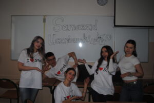 Grupa uczniów w koszulkach „I ♥ Staś” pozuje przy tablicy z napisem „Samorząd Uczniowski”.