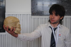 Uczeń trzyma model czaszki i patrzy na niego, jakby analizował budowę anatomiczną.