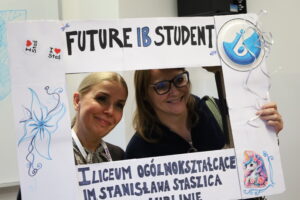 Dwie kobiety uśmiechają się, patrząc przez ozdobną ramkę z napisem „FUTURE IB STUDENT” i nazwą liceum im. Stanisława Staszica w Lublinie. Ramka ozdobiona rysunkami i naklejkami.