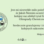Grafika na jasnym, zielonym tle z informacją o sukcesie ucznia. Po lewej okrągłe logo „Olimpiada Chemiczna od 1954 roku” z symbolami kolb w różnych kolorach. Po prawej tekst gratulacyjny informujący, że Jakub Niemira, uczeń klasy 4d, ponownie zdobył tytuł finalisty Olimpiady Chemicznej. Na dole podpis „Małgorzata Kasprzak” oraz informacja „440 lat 1586–2026”.