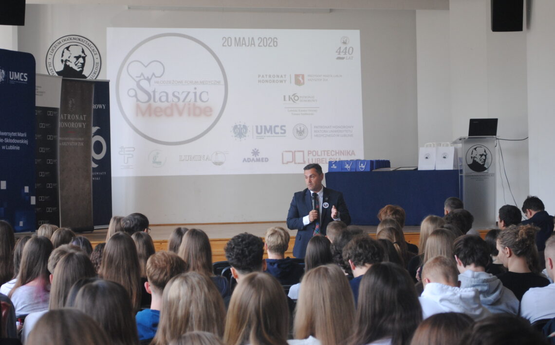 Aula szkolna podczas konferencji medycznej „Staszic MedVibe”. Prelegent przemawia do licznie zgromadzonych uczniów, a na ekranie wyświetlona jest prezentacja wydarzenia.