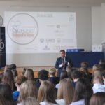 Aula szkolna podczas konferencji medycznej „Staszic MedVibe”. Prelegent przemawia do licznie zgromadzonych uczniów, a na ekranie wyświetlona jest prezentacja wydarzenia.