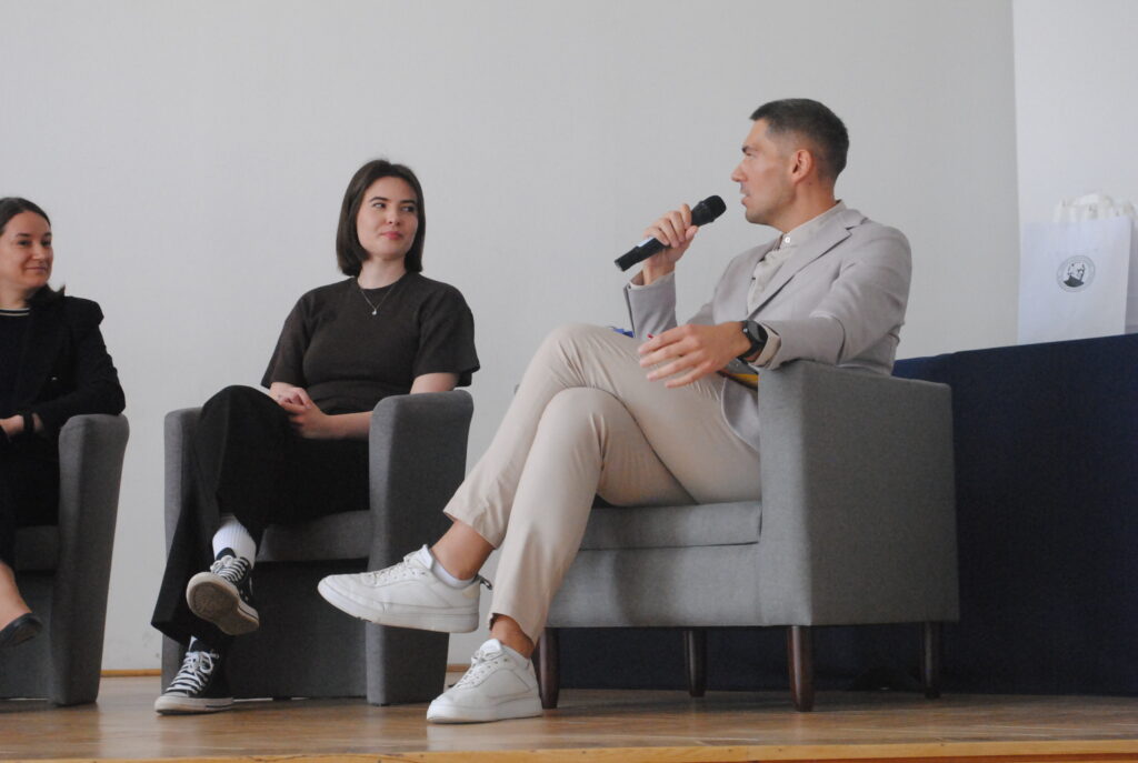 Rozmowa panelowa – mężczyzna z mikrofonem odpowiada na pytania podczas spotkania.