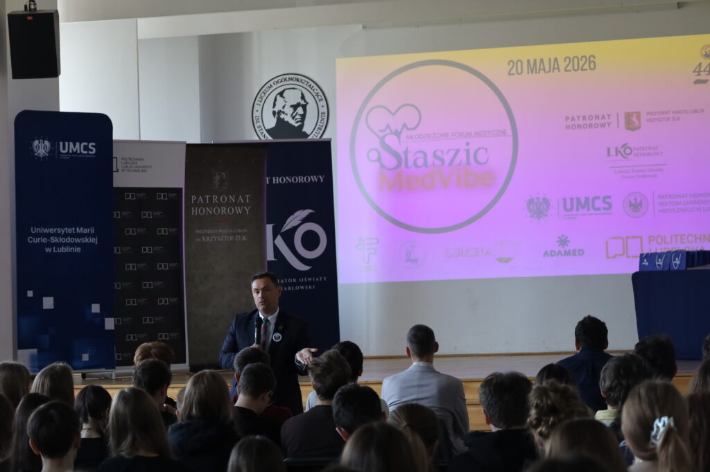 Prelegent prowadzi spotkanie podczas konferencji „Staszic MedVibe”, widoczna prezentacja i publiczność.