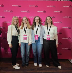 Cztery kobiety pozują do wspólnego zdjęcia przed różową ścianką promocyjną z powtarzającym się logo „zwolnieni z teorii”. Jedna osoba ma zielony identyfikator nauczycielki, trzy pozostałe różowe identyfikatory finalistek. Wszystkie patrzą w stronę aparatu.