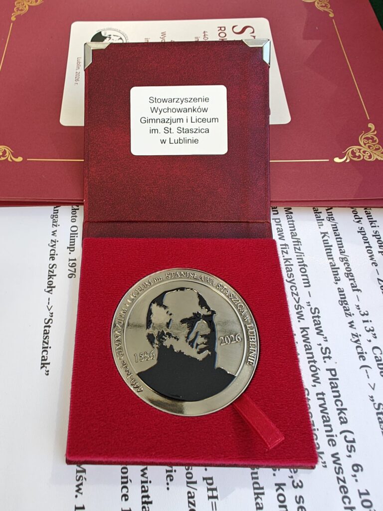 Zbliżenie okrągłego jubileuszowego medalu z wizerunkiem Stanisława Staszica i datami „1586” oraz „2026”, umieszczonego w czerwonym etui. Na wieczku widnieje napis „Stowarzyszenie Wychowanków Gimnazjum i Liceum im. St. Staszica w Lublinie”.
