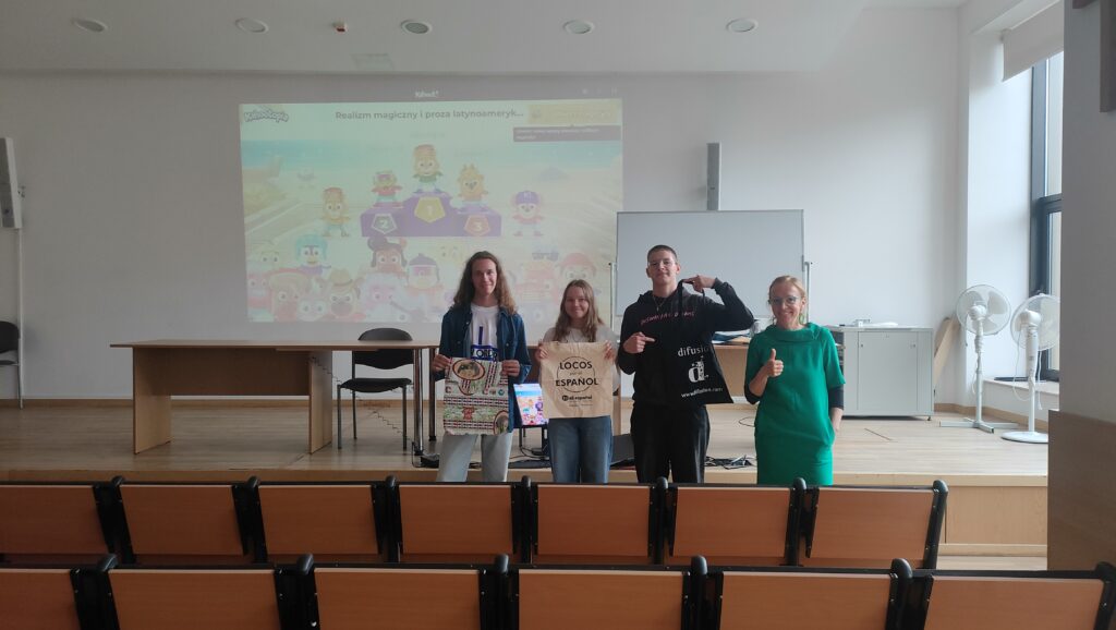 Troje uczestników wraz z prowadzącą prezentuje nagrody po quizie Kahoot dotyczącym realizmu magicznego i prozy latynoamerykańskiej.