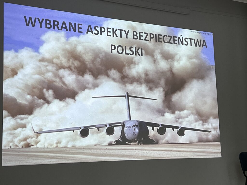 Slajd tytułowy prezentacji „Wybrane aspekty bezpieczeństwa Polski” ze zdjęciem samolotu na tle chmur.