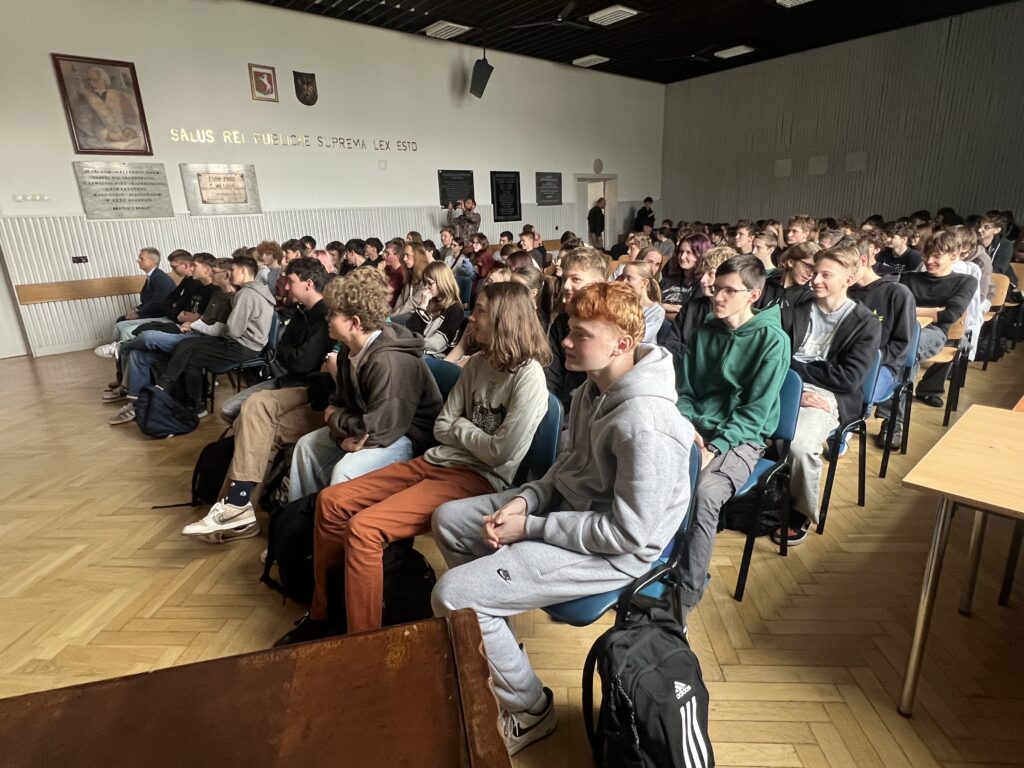 Uczestnicy wykładu siedzą w rzędach krzeseł w sali konferencyjnej.