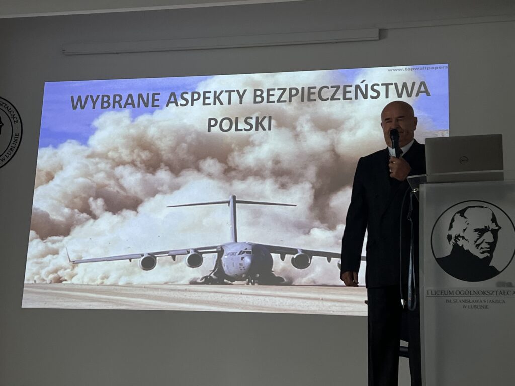 Mężczyzna prowadzi wykład przy slajdzie „Wybrane aspekty bezpieczeństwa Polski”.