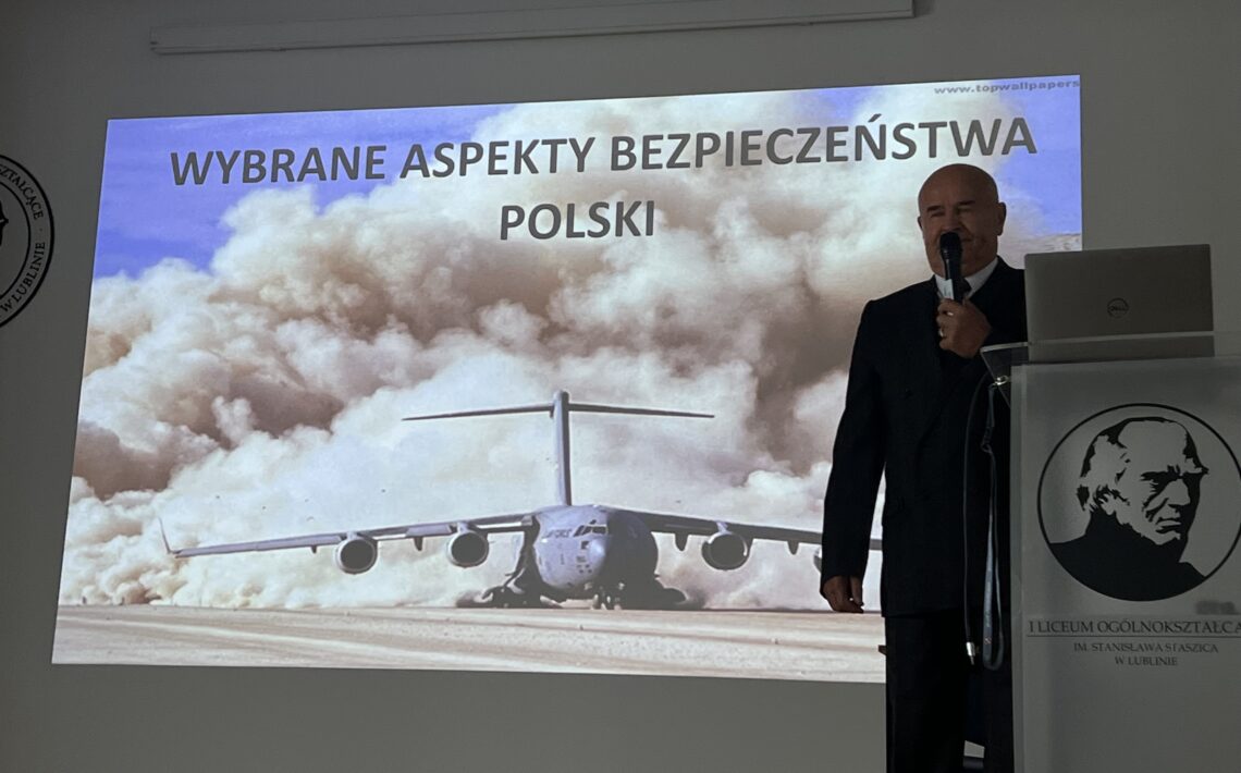 Mężczyzna prowadzi wykład przy slajdzie „Wybrane aspekty bezpieczeństwa Polski”.