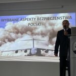 Mężczyzna prowadzi wykład przy slajdzie „Wybrane aspekty bezpieczeństwa Polski”.